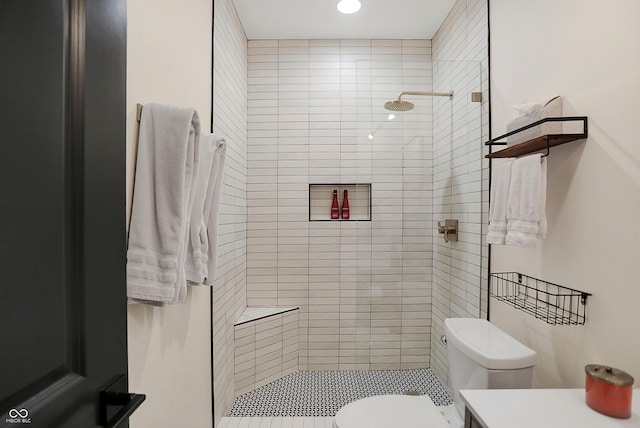 bathroom with a tile shower, vanity, and toilet