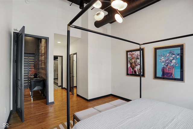 bedroom featuring ceiling fan, a towering ceiling, and hardwood / wood-style floors