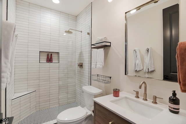 bathroom featuring tiled shower, vanity, and toilet