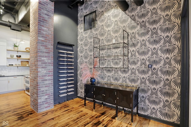 interior space with a towering ceiling, white cabinets, light wood-type flooring, stainless steel range oven, and sink