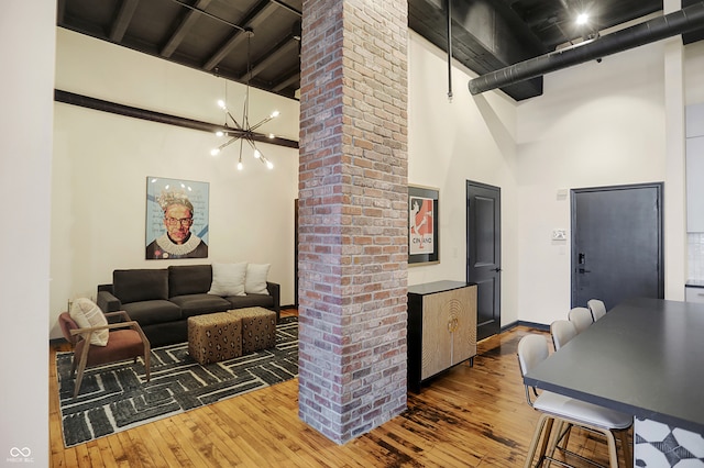 interior space with ornate columns, an inviting chandelier, a towering ceiling, and dark wood-type flooring