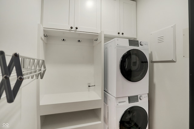 laundry area with stacked washer and clothes dryer and cabinets