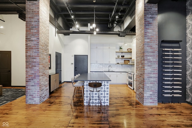 kitchen featuring a center island, a towering ceiling, light hardwood / wood-style flooring, and white cabinets