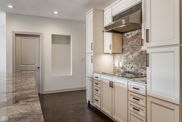 kitchen featuring backsplash, wall chimney range hood, black electric cooktop, dark hardwood / wood-style floors, and light stone countertops