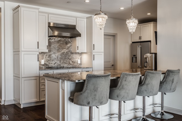 kitchen featuring stainless steel fridge, black electric stovetop, range hood, and a breakfast bar