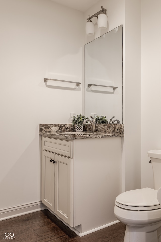 bathroom with wood-type flooring, vanity, and toilet