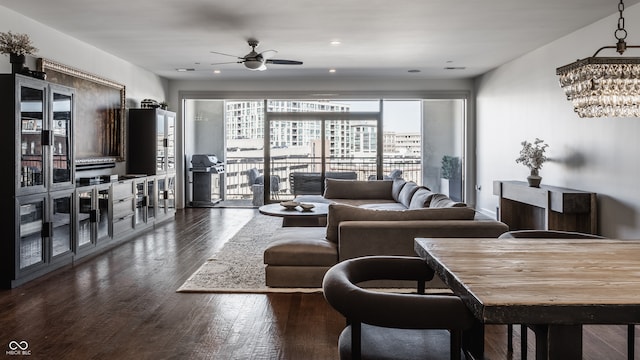 living room with ceiling fan with notable chandelier and dark hardwood / wood-style flooring