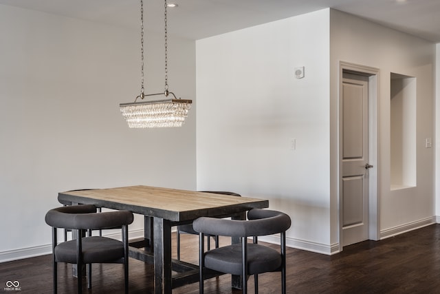 dining room with dark hardwood / wood-style flooring and a chandelier