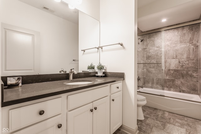 full bathroom with tiled shower / bath, vanity, and toilet