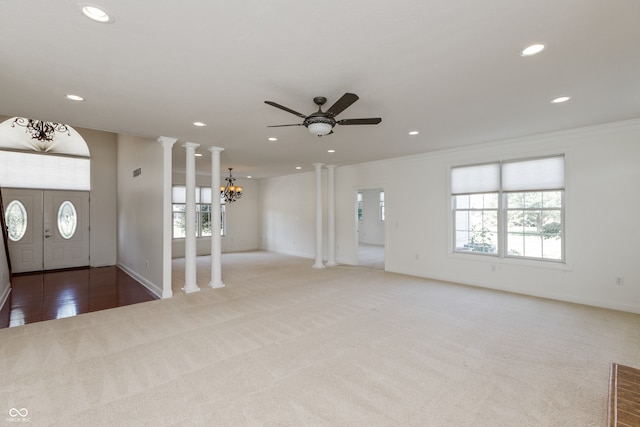 carpeted entrance foyer with crown molding, decorative columns, and ceiling fan with notable chandelier