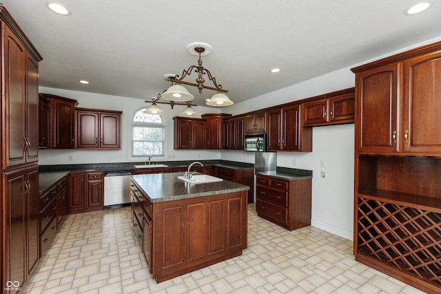 kitchen with sink, an island with sink, hanging light fixtures, and stainless steel appliances