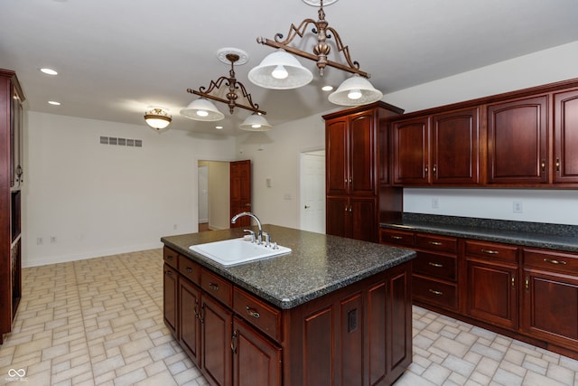 kitchen with a notable chandelier, sink, decorative light fixtures, and a kitchen island with sink