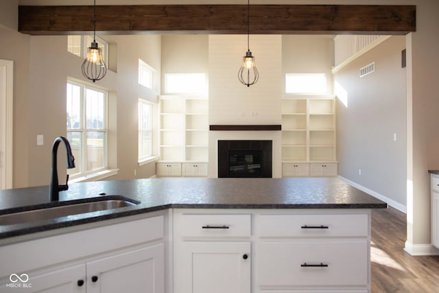 kitchen featuring hanging light fixtures, sink, and white cabinets