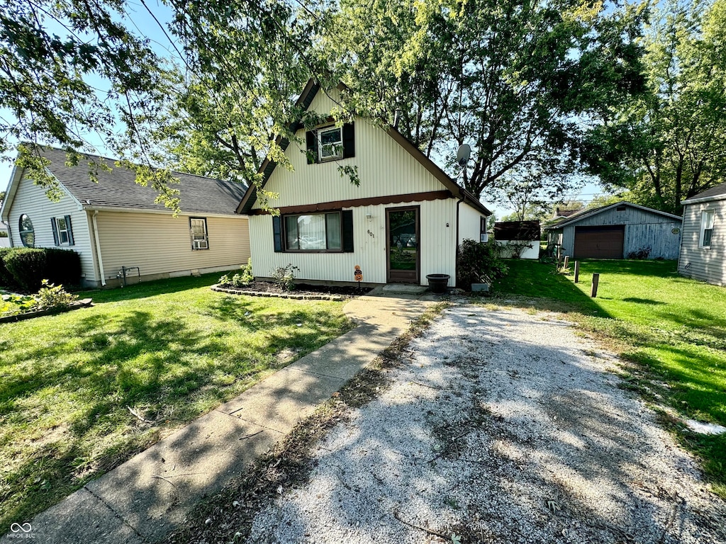 view of front of property featuring a front yard, a garage, and an outbuilding