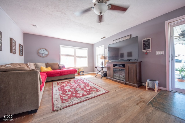 living room featuring light wood-type flooring, a textured ceiling, and ceiling fan