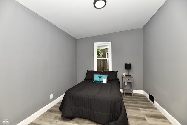 bedroom featuring light wood-type flooring and vaulted ceiling