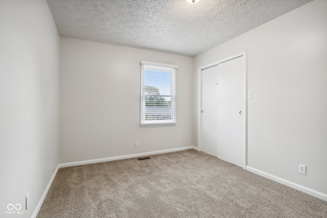 carpeted spare room featuring a textured ceiling