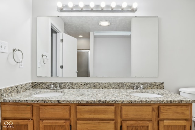 bathroom featuring walk in shower, a textured ceiling, vanity, and toilet