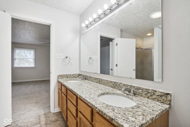 bathroom featuring a textured ceiling, tile patterned flooring, vanity, and a shower with door