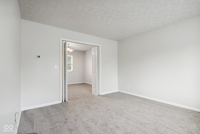 carpeted empty room featuring a textured ceiling