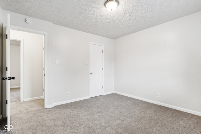 empty room with carpet floors and a textured ceiling