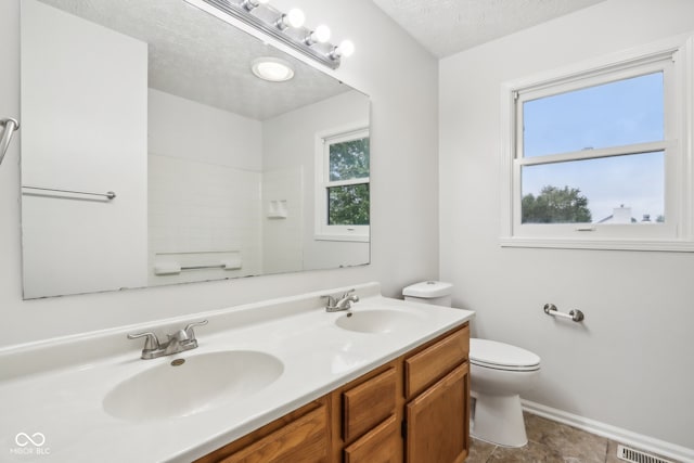 bathroom featuring vanity, a textured ceiling, a healthy amount of sunlight, and toilet