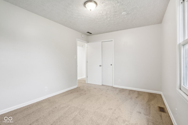 empty room featuring light colored carpet and a textured ceiling