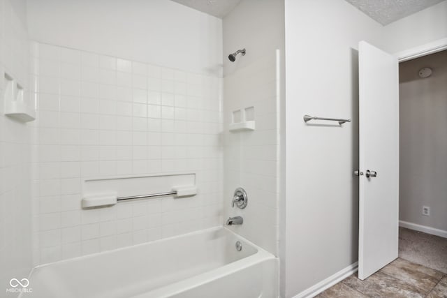 bathroom featuring a textured ceiling and tiled shower / bath combo