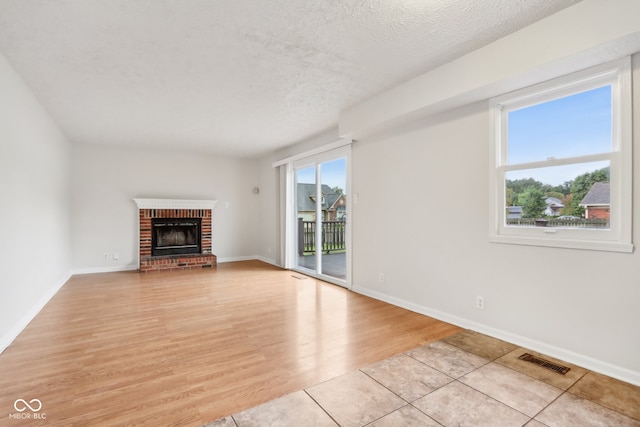 unfurnished living room with a textured ceiling, light wood-type flooring, and a wealth of natural light