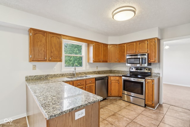 kitchen with a textured ceiling, kitchen peninsula, appliances with stainless steel finishes, and sink