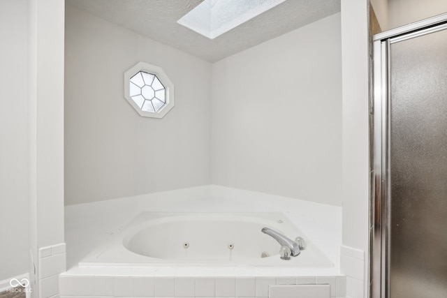 bathroom with a skylight, separate shower and tub, and a textured ceiling