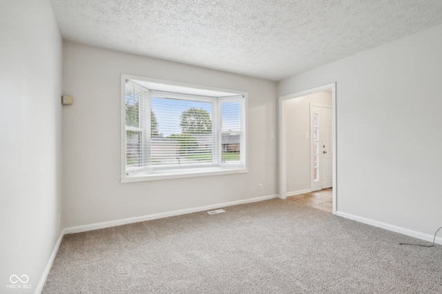 carpeted empty room with a textured ceiling