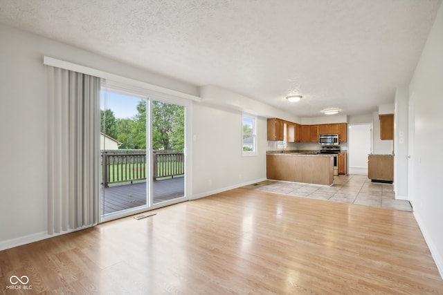 unfurnished living room featuring a textured ceiling, light hardwood / wood-style flooring, and a wealth of natural light