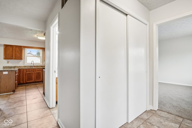 hall featuring a textured ceiling, sink, and light tile patterned floors