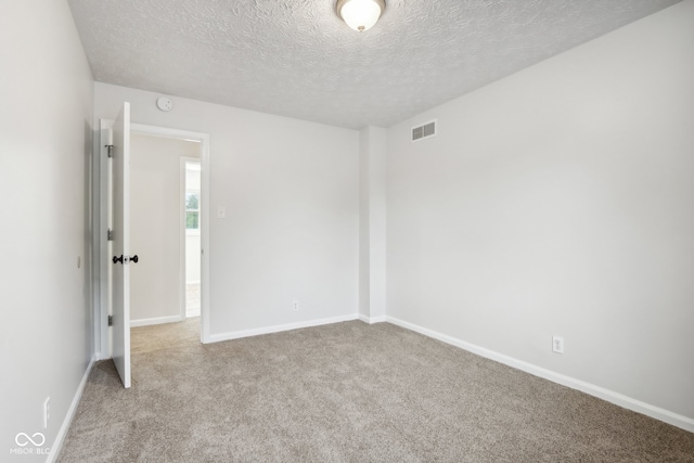 carpeted empty room with a textured ceiling