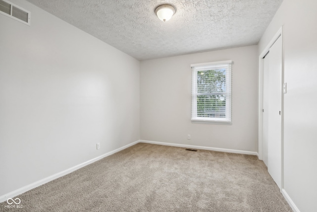 spare room with a textured ceiling and carpet floors