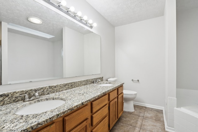 bathroom featuring a bathtub, vanity, a textured ceiling, toilet, and tile patterned floors