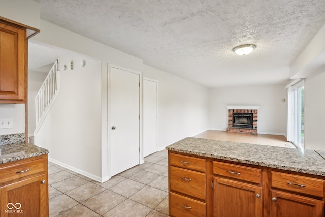 kitchen featuring light stone counters, a textured ceiling, a fireplace, and light tile patterned flooring