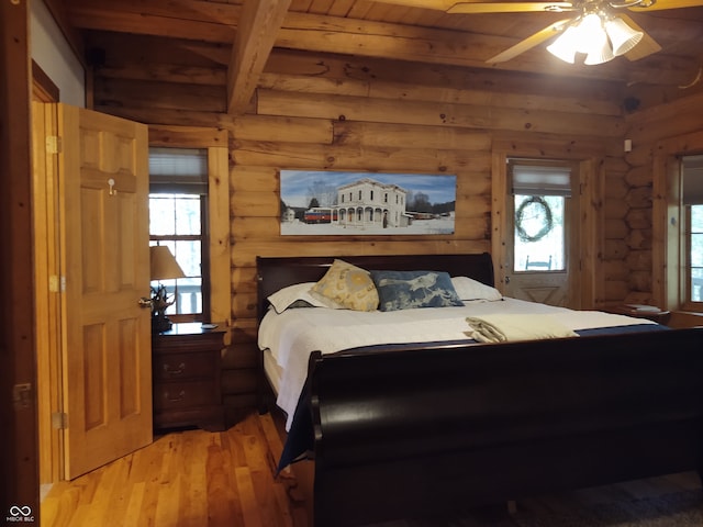 bedroom with beam ceiling, light hardwood / wood-style flooring, multiple windows, and ceiling fan