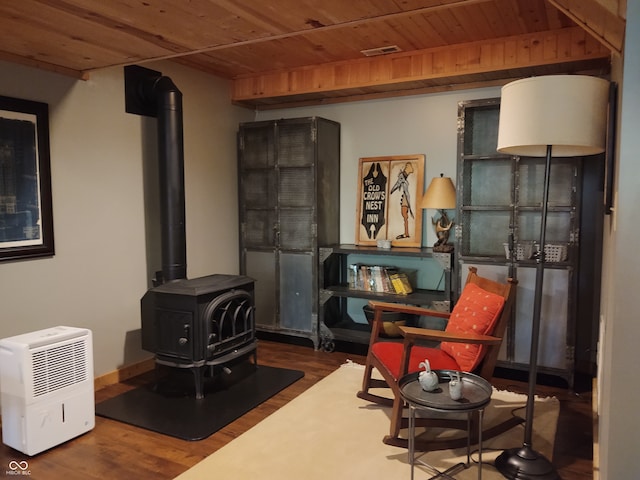 sitting room featuring hardwood / wood-style flooring, a wood stove, and wooden ceiling