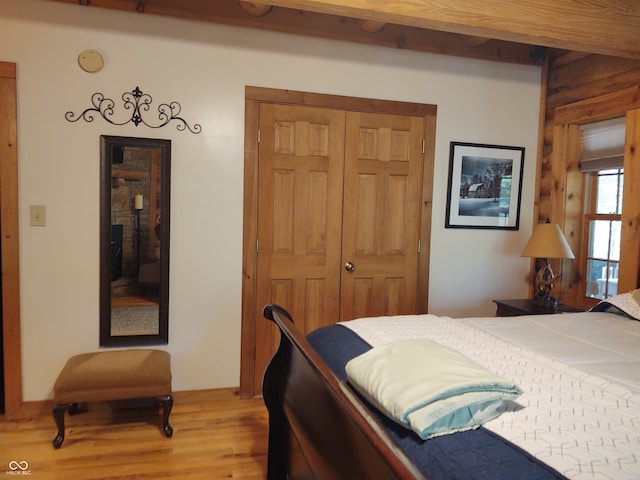 bedroom with light hardwood / wood-style flooring, wood walls, and a closet