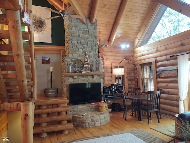 living room featuring beam ceiling, rustic walls, light wood-type flooring, high vaulted ceiling, and ceiling fan