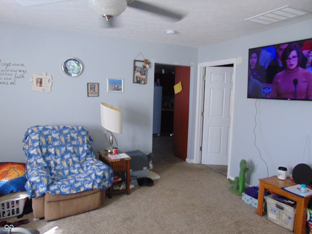 living area with ceiling fan and carpet