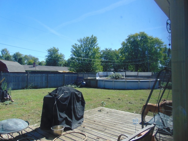 wooden deck with area for grilling, a fenced in pool, and a lawn