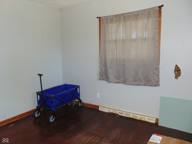 spare room featuring a baseboard heating unit and hardwood / wood-style floors