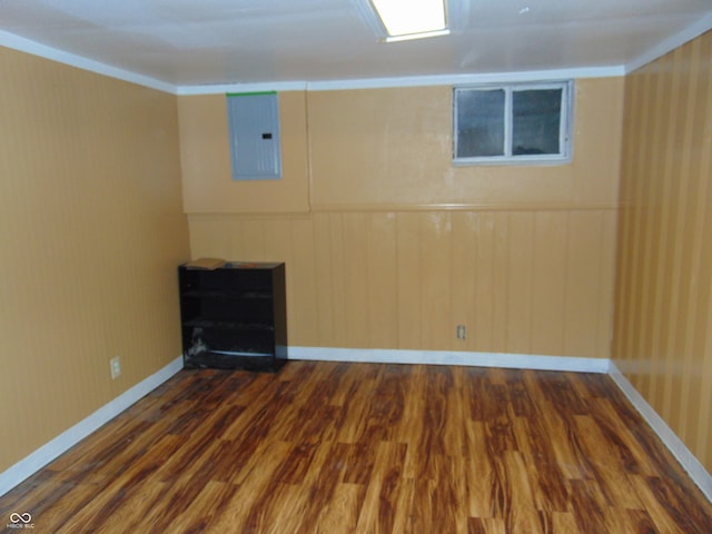 basement featuring ornamental molding, electric panel, and dark hardwood / wood-style floors