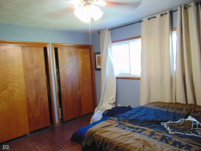 bedroom featuring two closets, ceiling fan, and dark hardwood / wood-style floors