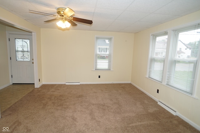 carpeted spare room with ceiling fan, a drop ceiling, and a baseboard heating unit