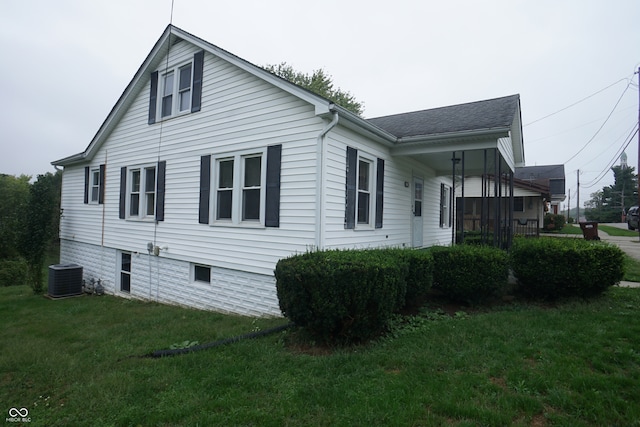 view of side of home with a yard and central AC