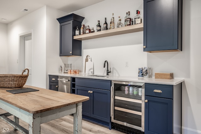 bar featuring light hardwood / wood-style floors, sink, blue cabinetry, and wine cooler